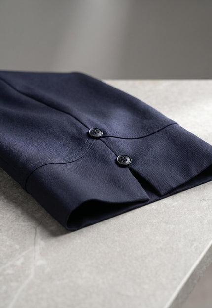 Κοντινή λεπτομέρεια στο σκούρο μπλε γυναικείο παντελόνι 7/8 για μεγάλα μεγέθη, όπου διακρίνεται το πλαϊνό σκίσιμο και τα δύο κουμπιά στο μπατζάκι.