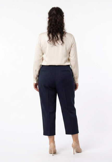Πίσω όψη από επίσημο γυναικείο παντελόνι plus size σε μπλε σκούρο χρώμα. Μήκος 7/8 σε ίσια γραμμή, φορεμένο από μοντέλο σε λευκό φόντο.