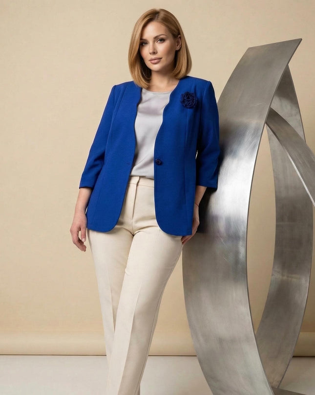 Επίσημο γυναικείο σακάκι μεγάλα μεγέθη σε μπλε ρουά με διακοσμητικό τριαντάφυλλο. Λήψη στα 3/4, φορεμένο με μπεζ παντελόνι.