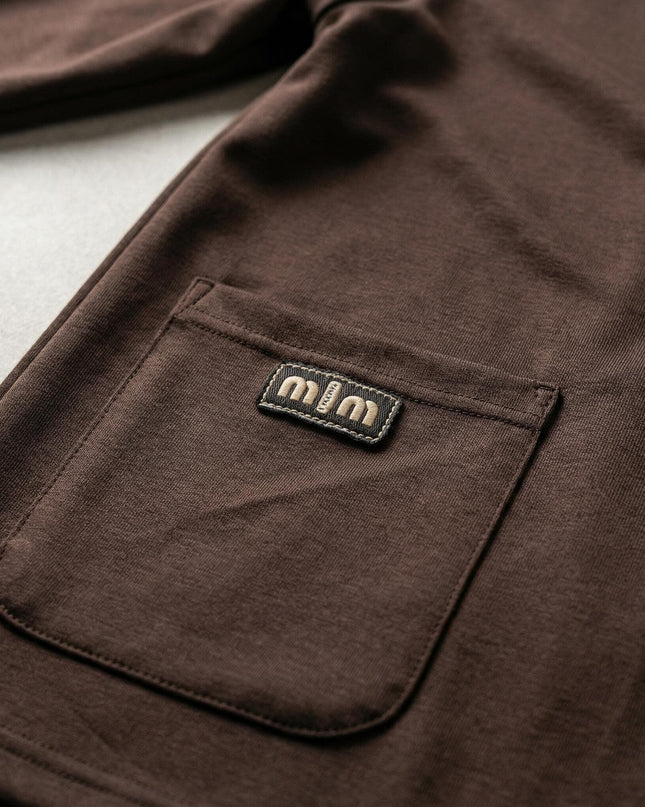 Κοντινή λεπτομέρεια της τσέπης με διακοσμητικό στοιχείο σε επίσημο γυναικείο σετ καφέ χρώμα plus size, που αναδεικνύει την ποιότητα του υφάσματος.