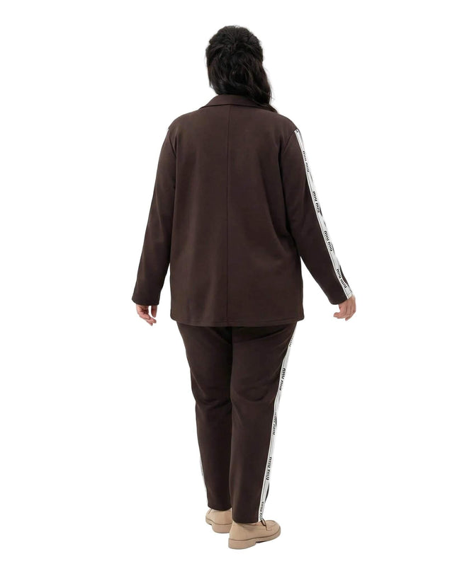 Επίσημο γυναικείο σετ δύο τεμαχίων σε καφέ χρώμα plus size, σε ολόσωμη λήψη που δείχνει την πίσω όψη με τις χαρακτηριστικές λευκές ρίγες στα μανίκια και το παντελόνι.