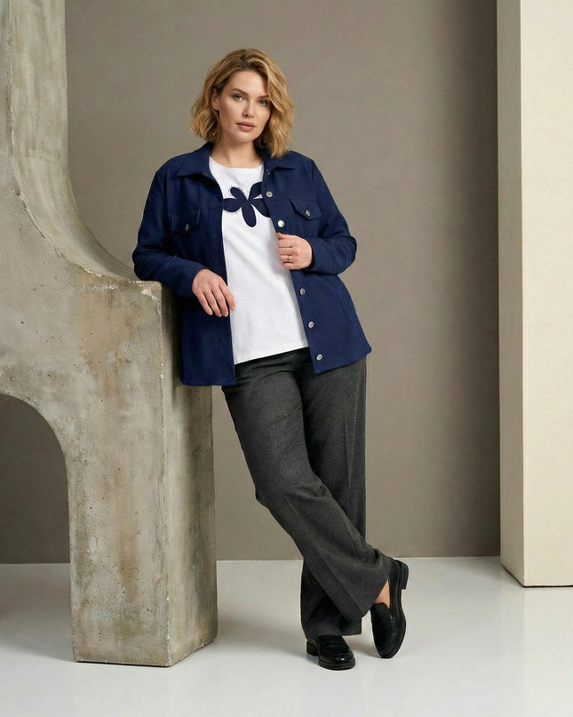 Ολόσωμη λήψη: Επίσημο γυναικείο σετ σε μεγάλα μεγέθη, με μπλε εβαζέ σακάκι και λευκό t-shirt που διαθέτει διακριτικό απλικέ σχέδιο.