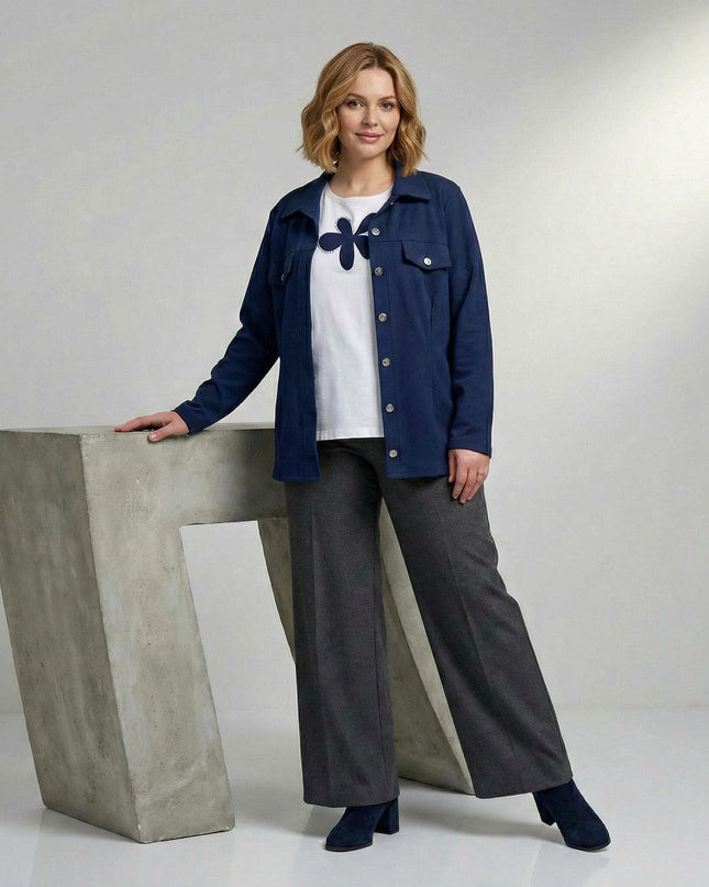 Ολόσωμη λήψη μοντέλου με επίσημο γυναικείο σετ σε μεγάλα μεγέθη, που περιλαμβάνει μπλε σακάκι με κουμπιά και λευκό t-shirt με μπλε απλικέ λουλούδι.