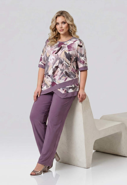 Ολόσωμη λήψη: Επίσημο γυναικείο σετ plus size. Ασύμμετρη τουνίκ με αφηρημένο μοτίβο και άνετο παντελόνι σε απόχρωση σάπιο μήλο.