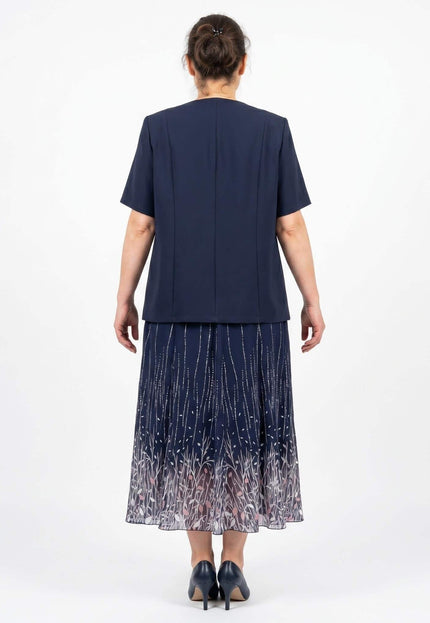 Πίσω όψη από επίσημο γυναικείο σετ plus size. Μπλε σκούρο κοντομάνικο σακάκι και αέρινη μίντι φούστα με διακριτικό φλοράλ μοτίβο στο τελείωμα.