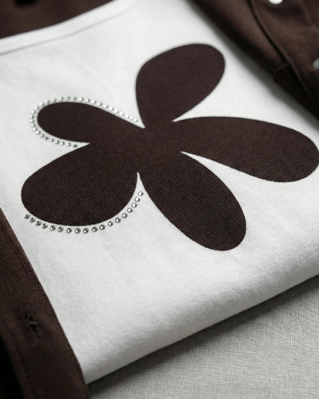 Κοντινή λεπτομέρεια σε plus size σετ δύο τεμαχίων: διακρίνεται το λευκό t-shirt με το καφέ φλοράλ απλικέ και στρας δίπλα στο καφέ ύφασμα του σακακιού.