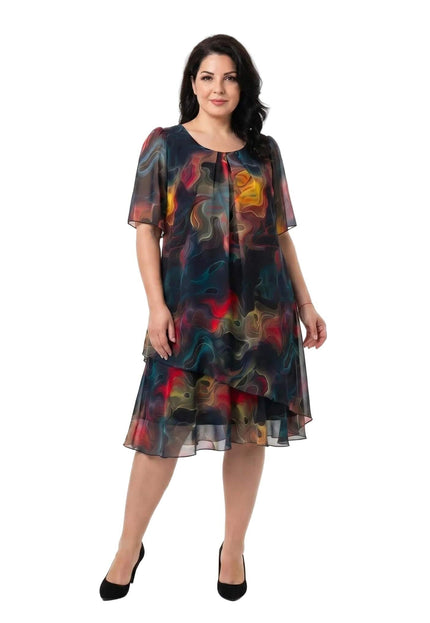 Ολόσωμη λήψη σε λευκό φόντο: Επίσημο καλοκαιρινό φόρεμα plus size από αέρινο σιφόν, με έντονο πολύχρωμο αφηρημένο μοτίβο και ασύμμετρο τελείωμα.