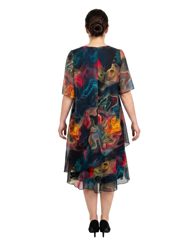 Πίσω όψη από επίσημο καλοκαιρινό φόρεμα plus size σε λευκό φόντο. Φτιαγμένο από ημιδιάφανο σιφόν με έντονο πολύχρωμο μοτίβο και ασύμμετρο τελείωμα.