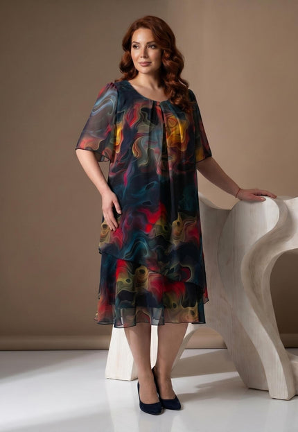 Ολόσωμη λήψη: Επίσημο καλοκαιρινό φόρεμα plus size από ημιδιάφανο σιφόν. Ξεχωρίζει το έντονο πολύχρωμο αφηρημένο μοτίβο και τα αέρινα μανίκια.