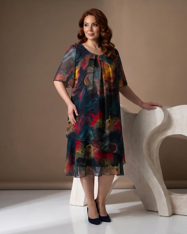 Ολόσωμη λήψη: Επίσημο καλοκαιρινό φόρεμα plus size από ημιδιάφανο σιφόν. Ξεχωρίζει το έντονο πολύχρωμο αφηρημένο μοτίβο και τα αέρινα μανίκια.