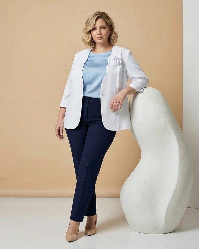 Ολόσωμη λήψη: Γυναίκα με επίσημο λευκό σακάκι σε μεγάλα μεγέθη, που διαθέτει μανίκια 7/8 και υφασμάτινη καρφίτσα τριαντάφυλλο στο πέτο.