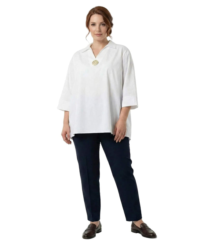 Ολόσωμη λήψη με γυναικείο λευκό βαμβακερό πουκάμισο σε μεγάλα μεγέθη, διακοσμημένο με καρφίτσα στο ντεκολτέ και άνετη ριχτή γραμμή.