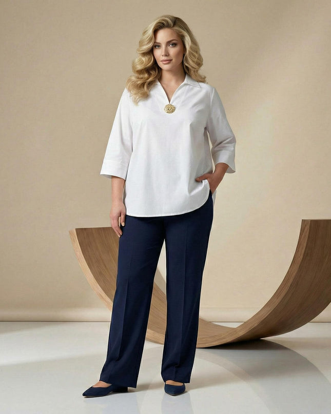 Ολόσωμη λήψη με γυναικείο λευκό βαμβακερό πουκάμισο σε μεγάλα μεγέθη. Συνδυασμένο με σκούρο μπλε παντελόνι, διαθέτει μανίκια 7/8 και διακοσμητική καρφίτσα στο στήθος.