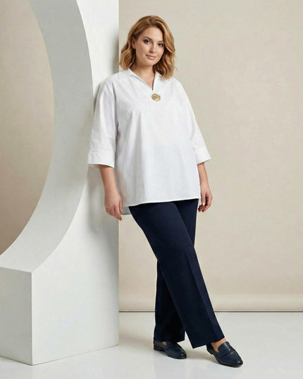 Ολόσωμη λήψη με επίσημο λευκό βαμβακερό πουκάμισο σε μεγάλα μεγέθη, φορεμένο με μπλε παντελόνι. Διαθέτει άνετη ριχτή γραμμή, μανίκια 7/8 και καρφίτσα.