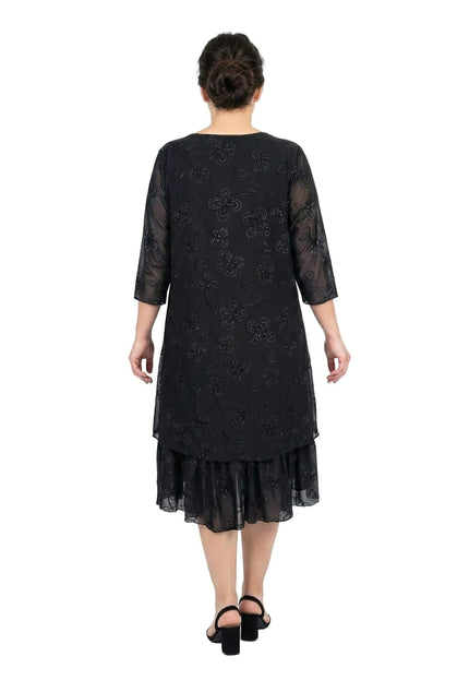 Επίσημο μαύρο φόρεμα plus size σε πίσω όψη, με λαμπερές πέτρες και φλοράλ μοτίβο. Διαθέτει διάφανα σιφόν μανίκια και βολάν στο τελείωμα.