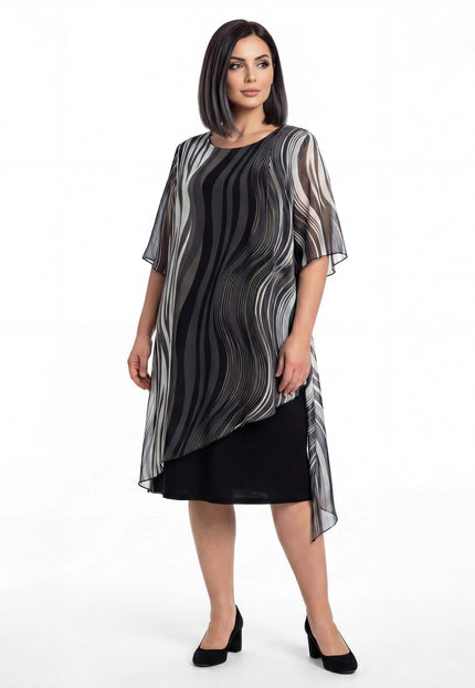 Επίσημο μαύρο φόρεμα plus size σε ολόσωμη λήψη, με ασύμμετρη αέρινη μουσελίνα και ιδιαίτερο ντεγκραντέ μοτίβο σε λευκό φόντο.