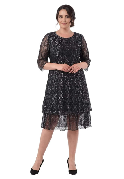 Ολόσωμη λήψη σε λευκό φόντο με επίσημο μαύρο φόρεμα σε μεγάλα μεγέθη, διακοσμημένο με εντυπωσιακή δαντέλα και μανίκια 3/4.