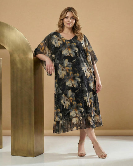 Αέρινο μαύρο φόρεμα σιφόν με φλοράλ μοτίβα και φαρδιά μανίκια για μεγάλα μεγέθη. Ολόσωμη λήψη που προβάλλει την κομψή εβαζέ γραμμή και το βολάν στο τελείωμα.