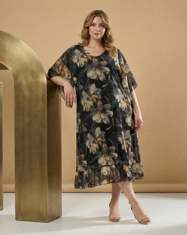 Αέρινο μαύρο φόρεμα σιφόν με φλοράλ μοτίβα και φαρδιά μανίκια για μεγάλα μεγέθη. Ολόσωμη λήψη που προβάλλει την κομψή εβαζέ γραμμή και το βολάν στο τελείωμα.