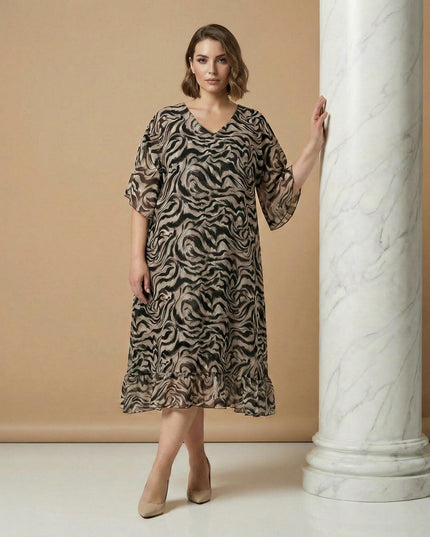 Κομψό φόρεμα σιφόν σε μεγάλα μεγέθη με μαύρο και μπεζ αφηρημένο σχέδιο, V λαιμόκοψη και αέρινη εβαζέ γραμμή, σε ολόσωμη λήψη.