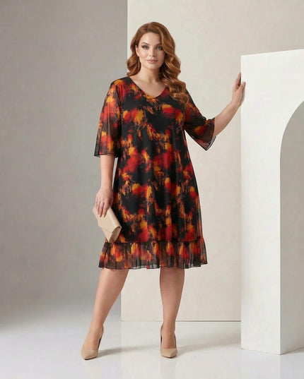 Ολόσωμη λήψη με μοντέλο που φοράει επίσημο μαύρο φόρεμα σε μεγάλα μεγέθη, με φλογερό εμπριμέ μοτίβο, V-ντεκολτέ και μανίκια από σιφόν.