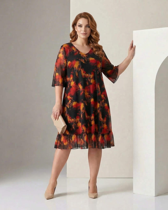 Ολόσωμη λήψη με μοντέλο που φοράει επίσημο μαύρο φόρεμα σε μεγάλα μεγέθη, με φλογερό εμπριμέ μοτίβο, V-ντεκολτέ και μανίκια από σιφόν.