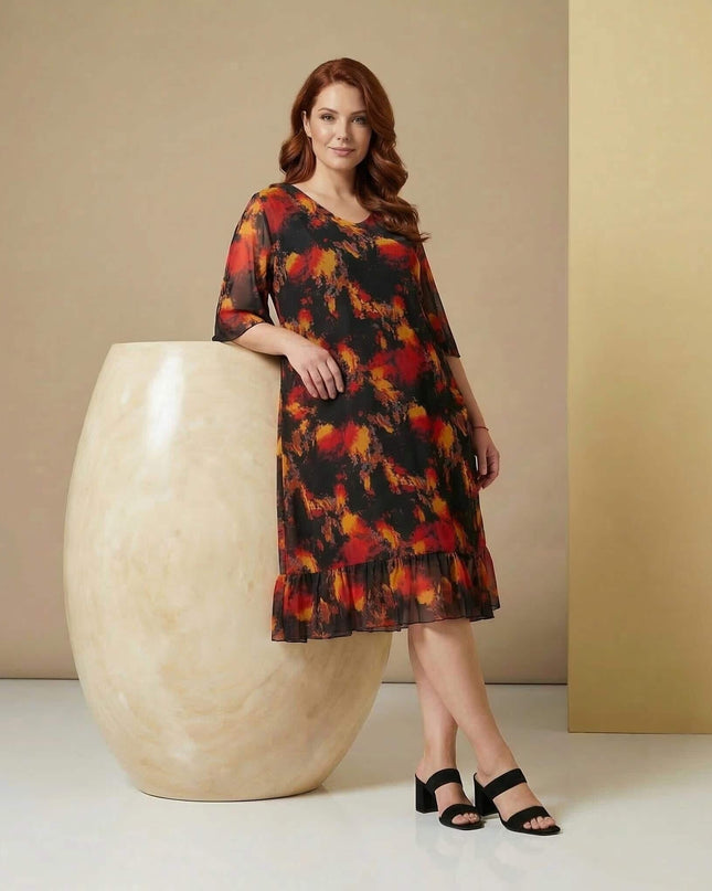 Ολόσωμη λήψη: Επίσημο μαύρο φόρεμα μεγάλα μεγέθη με εντυπωσιακό φλογερό εμπριμέ, ημιδιάφανα μανίκια από σιφόν και βολάν στο τελείωμα.