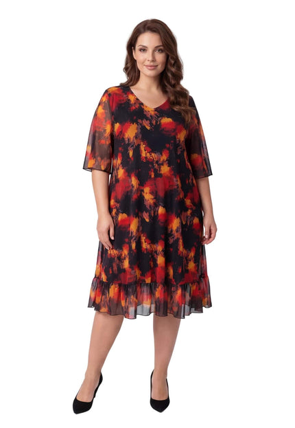 Ολόσωμη λήψη σε λευκό φόντο. Επίσημο μαύρο φόρεμα για μεγάλα μεγέθη με φλογερό εμπριμέ, V-ντεκολτέ και αέρινα μανίκια από σιφόν.