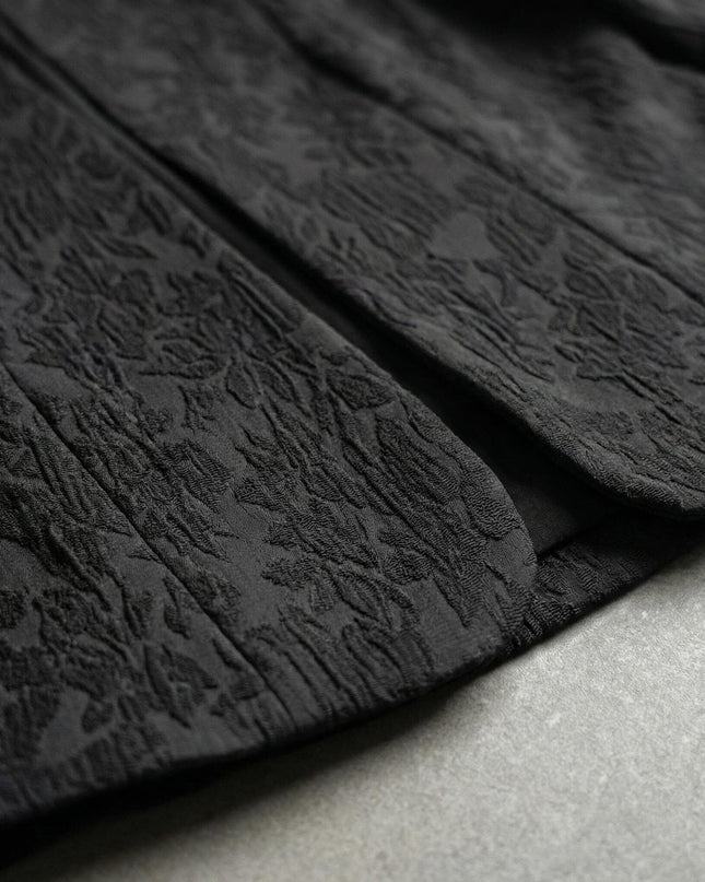Κοντινή λεπτομέρεια υφάσματος σε μαύρο επίσημο σακάκι για μεγάλα μεγέθη, με έμφαση στην ιδιαίτερη ανάγλυφη υφή και το προσεγμένο τελείωμα στο κάτω μέρος.