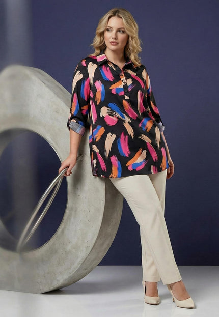 Ολόσωμη λήψη: Επίσημο μάξι πουκάμισο plus size με πολύχρωμο αφηρημένο μοτίβο και φαρδιά μανίκια, φορεμένο από μοντέλο με ανοιχτόχρωμο παντελόνι.