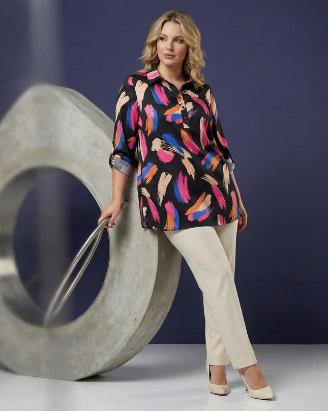 Ολόσωμη λήψη: Επίσημο μάξι πουκάμισο plus size με πολύχρωμο αφηρημένο μοτίβο και φαρδιά μανίκια, φορεμένο από μοντέλο με ανοιχτόχρωμο παντελόνι.