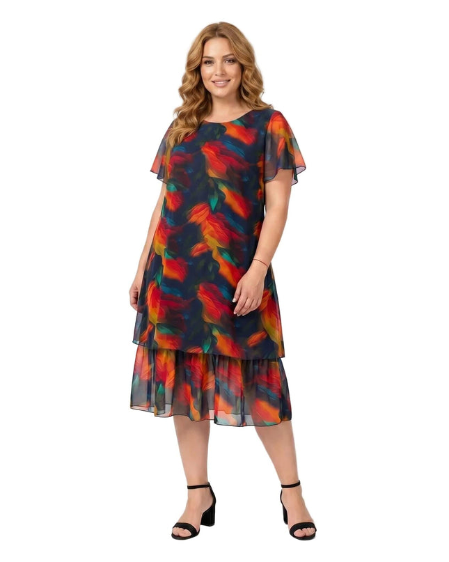 Ολόσωμη λήψη σε λευκό φόντο, όπου γυναίκα φοράει ένα κομψό επίσημο μίντι φόρεμα σε μεγάλα μεγέθη, με σκούρο μπλε αφηρημένο φλοράλ μοτίβο.