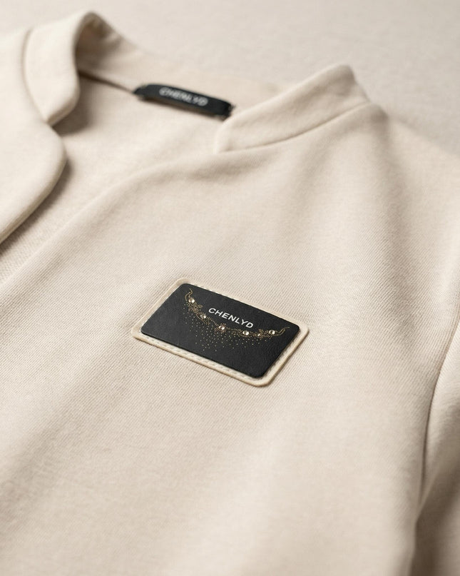 Κοντινή λεπτομέρεια του μπεζ σακακιού με το διακριτικό έμβλημα με στρασάκια, κομψό ρούχο σε μεγάλα μεγέθη.