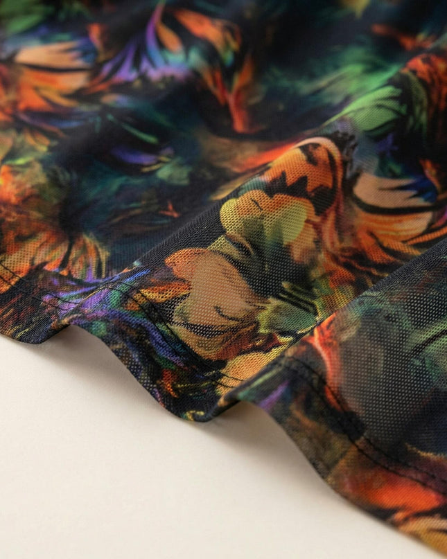 Κοντινή λήψη στο τελείωμα και την υφή του υφάσματος από επίσημο plus size φόρεμα, με πολύχρωμο εμπριμέ σχέδιο σε μαύρη βάση.