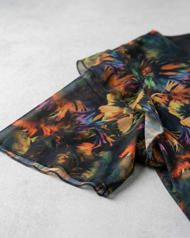 Κοντινή λεπτομέρεια στο εντυπωσιακό μανίκι με βολάν από επίσημο plus size φόρεμα, σε πολύχρωμο σιφόν ύφασμα με abstract μοτίβο.