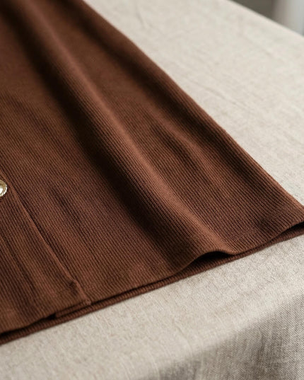 Κοντινή λεπτομέρεια της ριπ υφής και του χρυσού διακοσμητικού κουμπιού στο καφέ plus size μάξι φόρεμα.