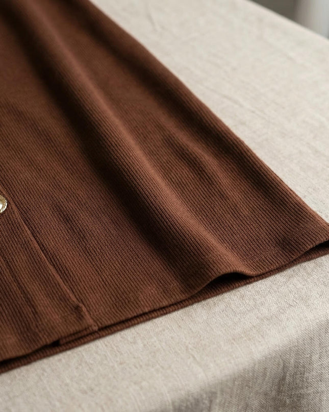 Κοντινή λεπτομέρεια της ριπ υφής και του χρυσού διακοσμητικού κουμπιού στο καφέ plus size μάξι φόρεμα.