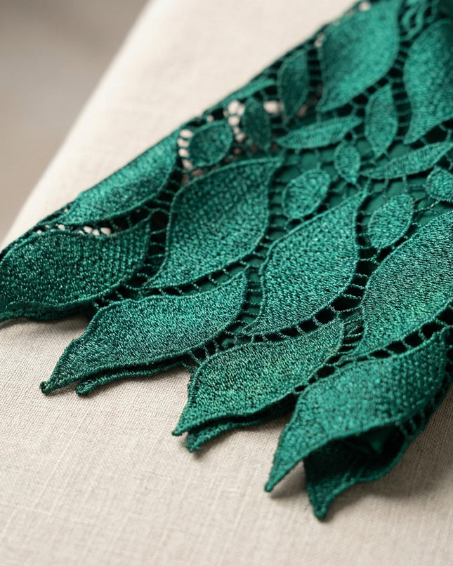 Κοντινή λεπτομέρεια στο τελείωμα του μανικιού με πράσινη δαντέλα σε σχέδιο φύλλων, από επίσημο φόρεμα σε μεγάλα μεγέθη.