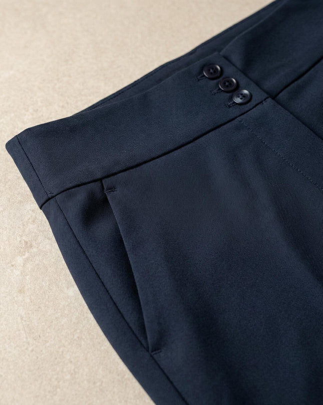 Κοντινή λεπτομέρεια σε επίσημο ψηλόμεσο μπλε παντελόνι μεγάλα μεγέθη, με εστίαση στα διακοσμητικά κουμπιά της ζώνης, την πλαϊνή τσέπη και την υφή του υφάσματος.