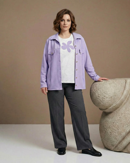 Ολόσωμη λήψη γυναικείου επίσημου σετ σε απαλό μωβ για μεγάλα μεγέθη, που περιλαμβάνει σακάκι με τσέπες και λευκή μπλούζα με απλικέ σχέδιο λουλουδιού.