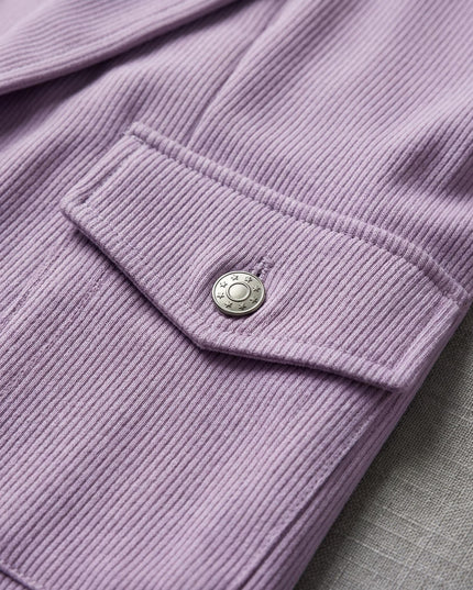 Κοντινή λεπτομέρεια σε μωβ σακάκι από επίσημο σετ για μεγάλα μεγέθη, εστιάζοντας στην ριμπ ύφανση και το διακοσμητικό μεταλλικό κουμπί στην τσέπη.