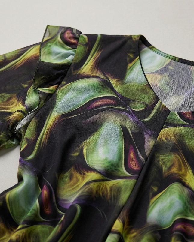 Κοντινή λεπτομέρεια από επίσημο σιφόν φόρεμα plus size με πολύχρωμο μοτίβο. Διακρίνονται οι πράσινες αποχρώσεις, η λαιμόκοψη και το βολάν στον ώμο.