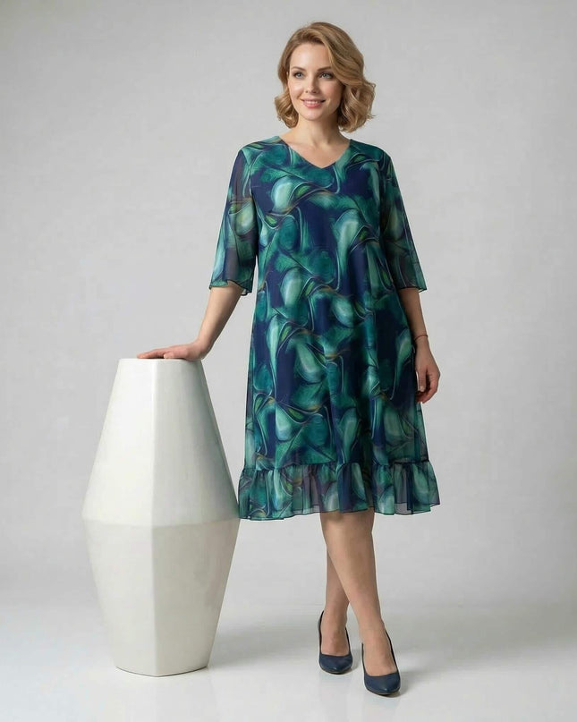 Ολόσωμη λήψη. Επίσημο σιφόν φόρεμα σε μεγάλα μεγέθη με ντεγκραντέ μπλε και πράσινο μοτίβο. Διαθέτει ημιδιάφανα μανίκια και βολάν στο τελείωμα.