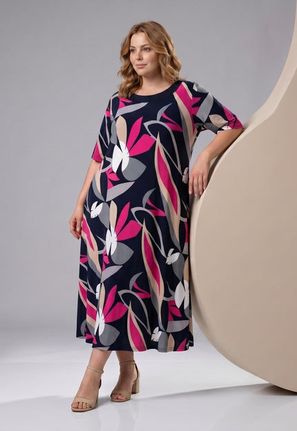 Ολόσωμη λήψη: plus size σκούρο μπλε μάξι φόρεμα σε γραμμή Α, με εντυπωσιακό ροζ και γκρι φλοράλ μοτίβο και κοντά μανίκια.