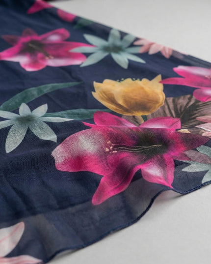 Κοντινή λεπτομέρεια υφάσματος για το σκούρο μπλε φόρεμα σε μεγάλα μεγέθη. Διακρίνεται το ημιδιάφανο φλοράλ σιφόν με ροζ και κίτρινα λουλούδια.