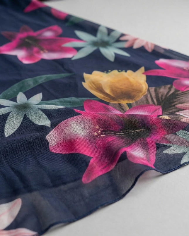 Κοντινή λεπτομέρεια υφάσματος για το σκούρο μπλε φόρεμα σε μεγάλα μεγέθη. Διακρίνεται το ημιδιάφανο φλοράλ σιφόν με ροζ και κίτρινα λουλούδια.