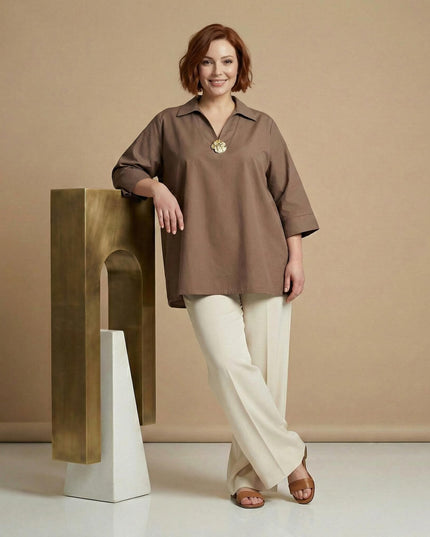 Ολόσωμη λήψη με γυναικείο επίσημο βαμβακερό πουκάμισο μόκα σε ριχτή γραμμή plus size, με γιακά, μανίκια 3/4 και διακοσμητική αγκράφα στο ντεκολτέ.