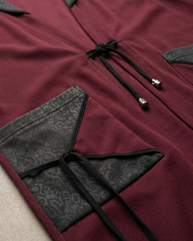 Κοντινή λεπτομέρεια σε εβαζέ μπορντό γιλέκο μεγάλα μεγέθη, εστιάζοντας στην τσέπη με ανάγλυφη δερματίνη και το δέσιμο με κορδόνια.