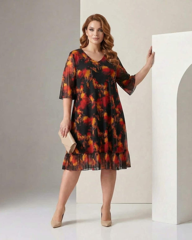 Γυναίκα φοράει φόρεμα με μαύρο και κόκκινο σχέδιο και στέκεται σε στούντιο με ουδέτερο φόντο