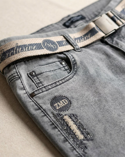 Κοντινή λεπτομέρεια σε γκρι καθημερινό τζιν παντελόνι μεγάλα μεγέθη, που δείχνει την υφασμάτινη ζώνη, την τσέπη και το έμβλημα ZMD με στρασάκια.
